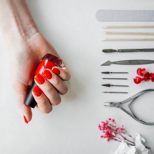 Manicured woman's nails with red nail polish. Tools of a manicure set on a white background.